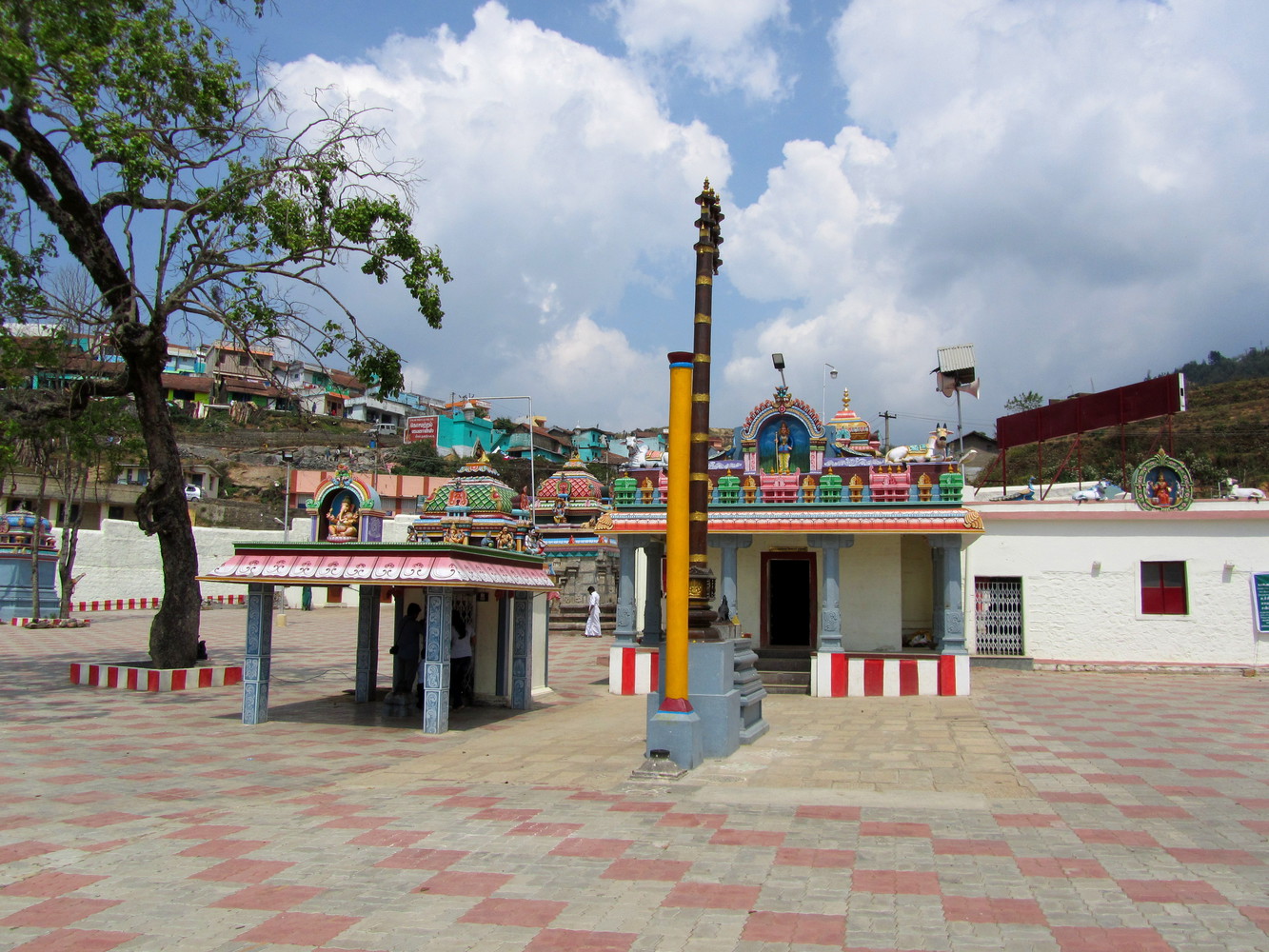 An enclosure of a temple with a pillar, a tree, and checkered floor