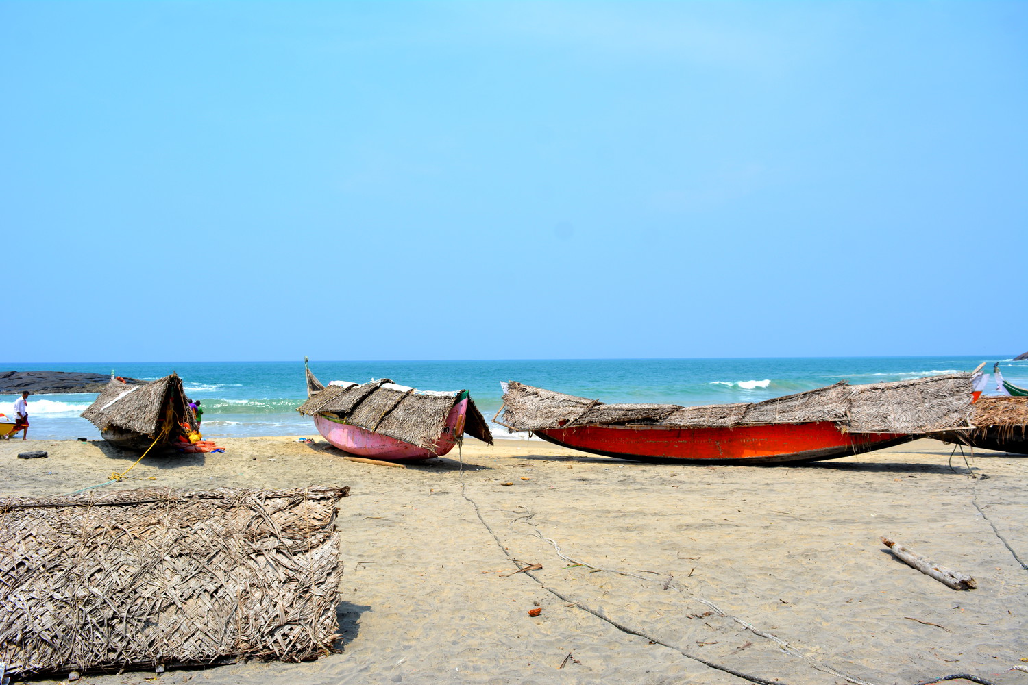 Traditional wooden fishing boats covered by thatched roofs at a sea beach