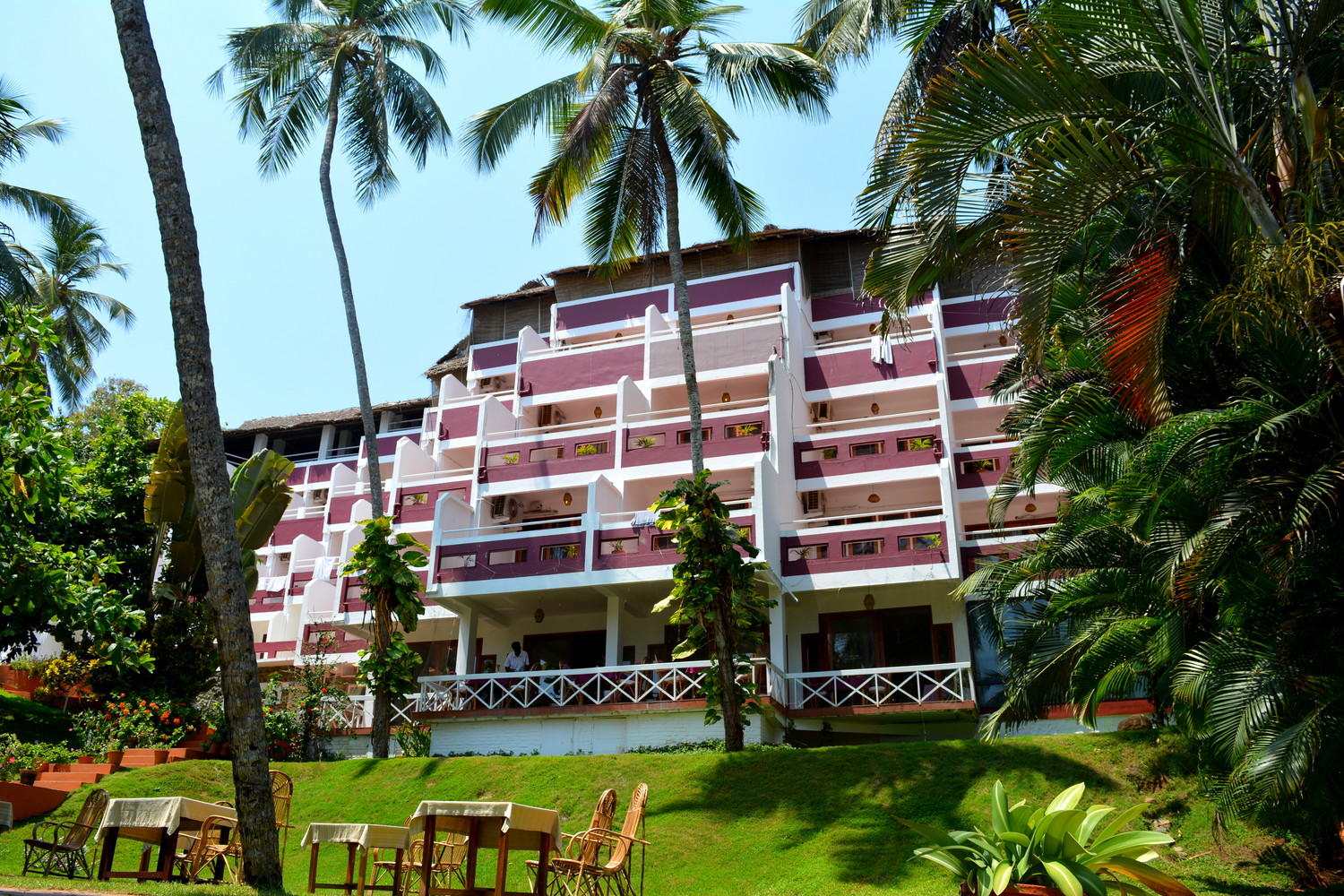 A multistorey hotel building atop a small hill covered with green lawn maintained by the hotel