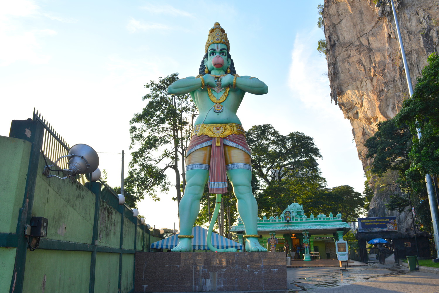 A tall statue of Lord Hanuman near a limestone hill of Batu Caves
