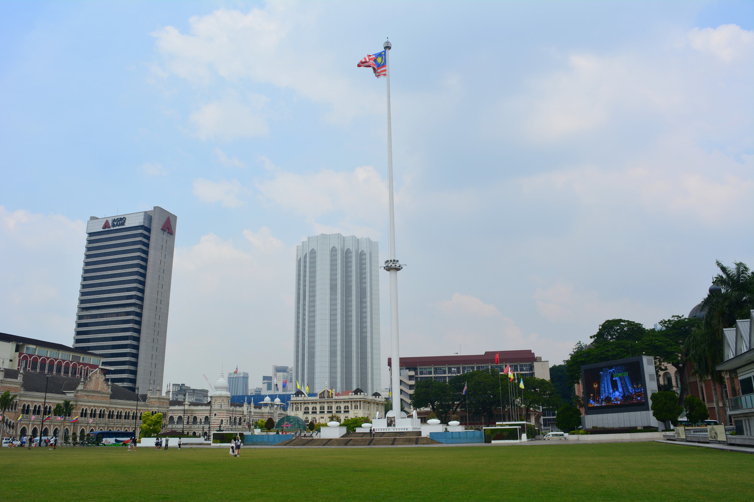 Merdeka square with green lawn and a flag pole at the centre with Malayan flag