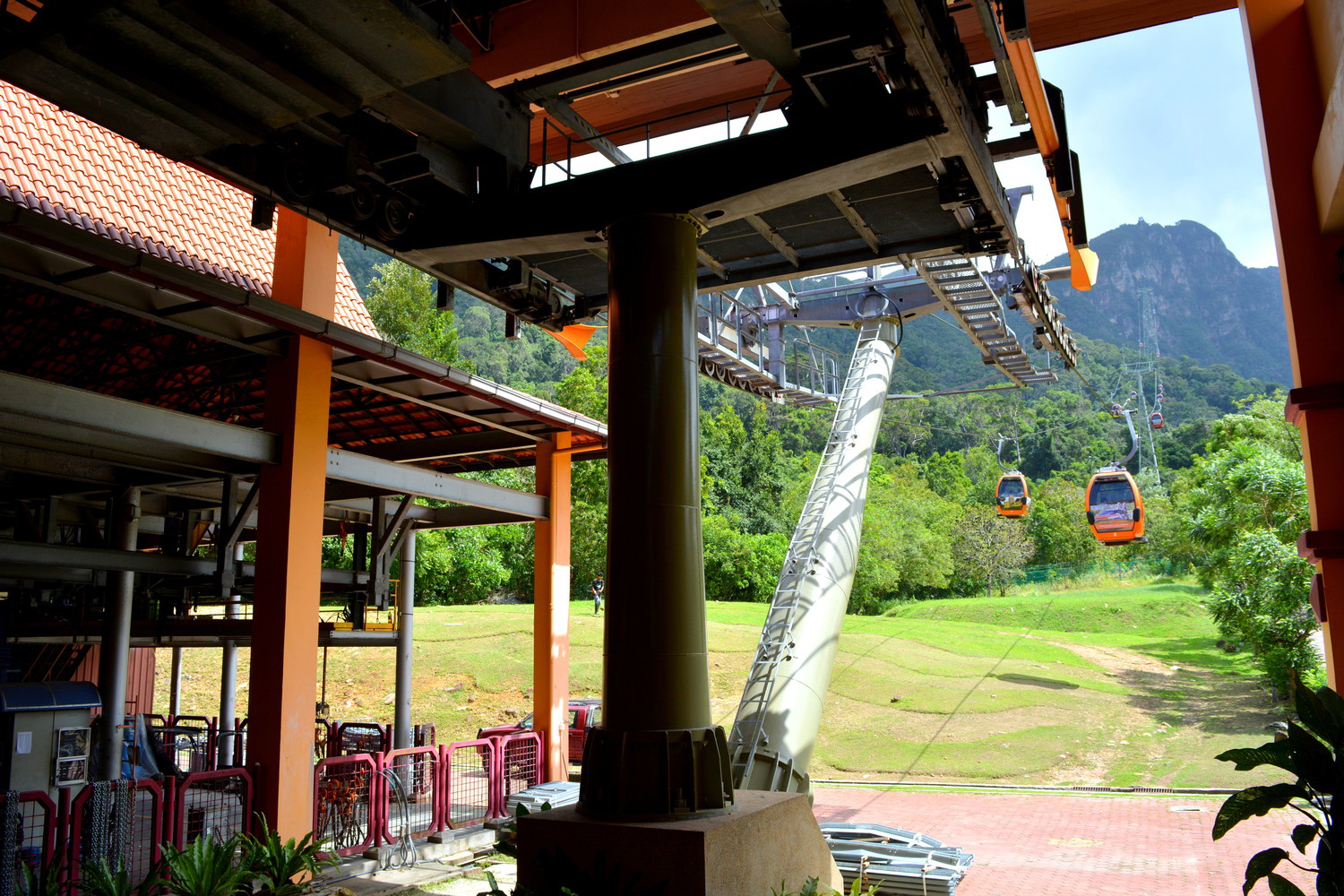 A cable car station with a cable car returning from a mountain to the station and another one going up to a mountain