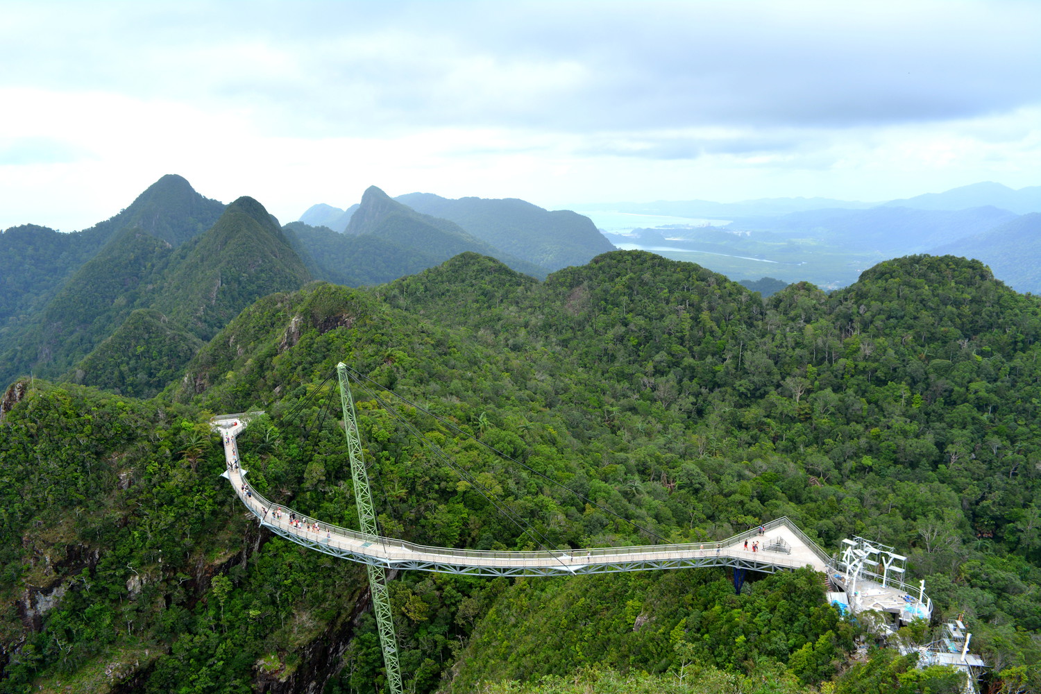 A curved walkway on a sky bridge that connects two hilltops of a mountain range