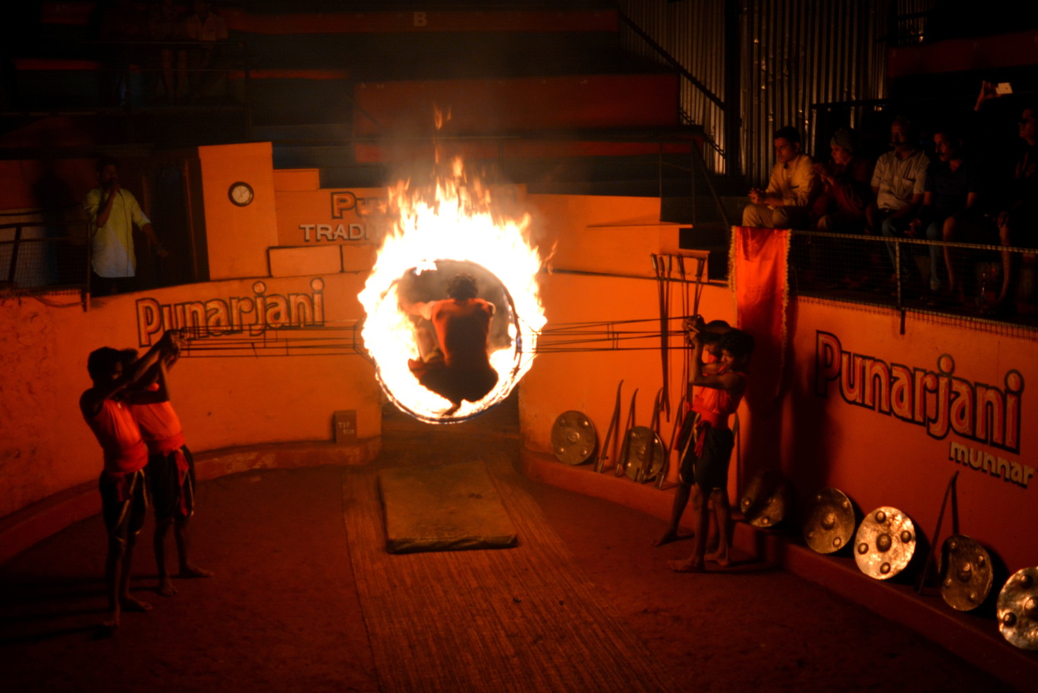 A martial artist jumping through a ring of fire held by other artists