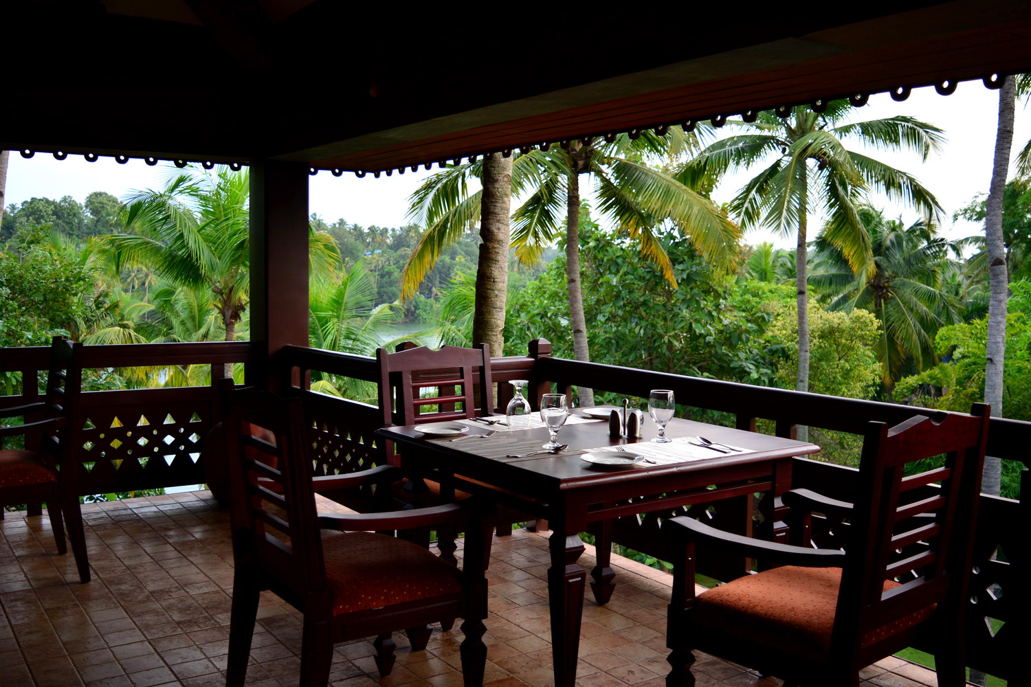 An open-air restaurant surrounded by coconut palm trees and other trees