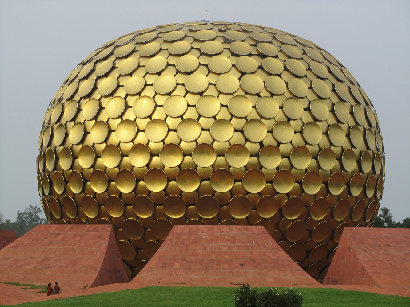 A huge golden metallic sphere supported by large orange petals