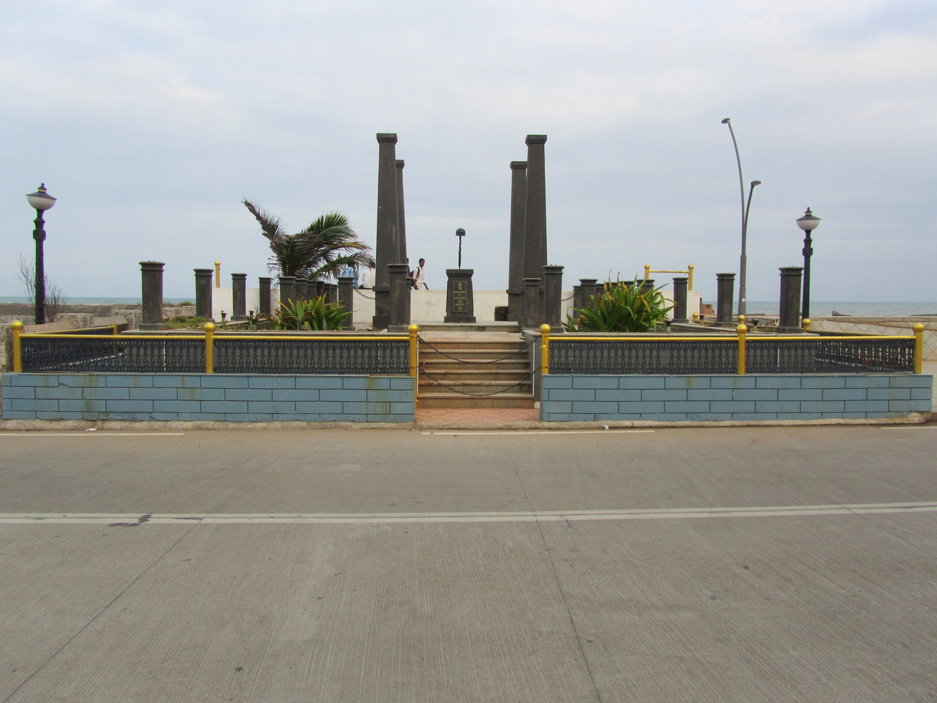 A memorial with four tall gray pillars, many small gray pillars, and a gray centopah at the centre with a rifle capped by a war helmet