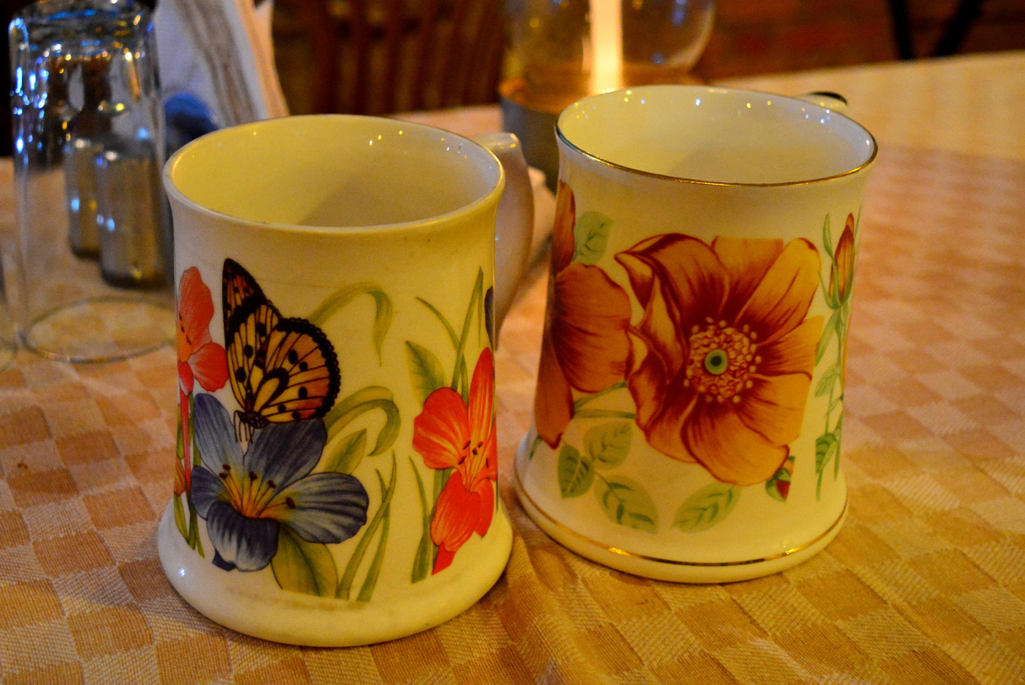 Two porcelain mugs with floral patterns painted on them