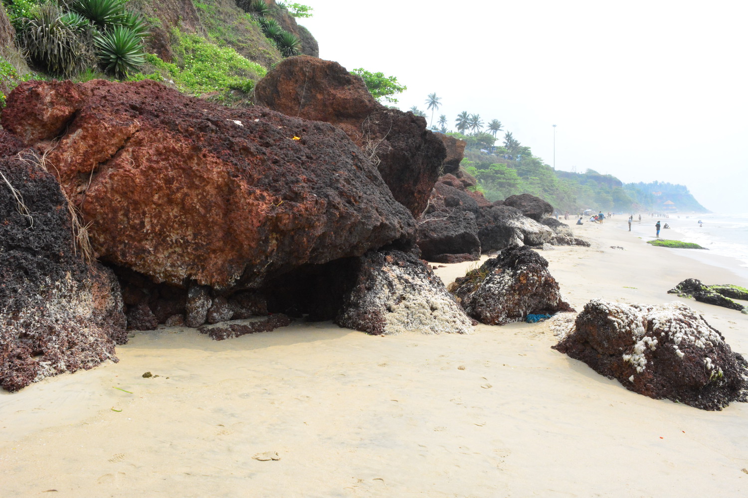 Large and small sedimentary rocks at the foot of a cliff beside a sea beach